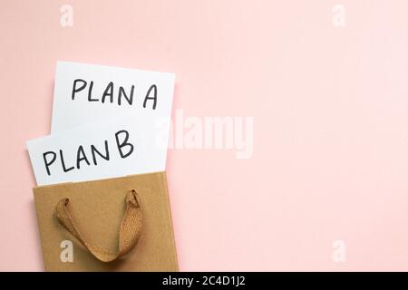 Plan A und Plan B in einem Kraftpapier-Beutel auf rosa Hintergrund. Businessplan, Wahl, Veränderung, Dilemma-Konzept. Draufsicht Stockfoto