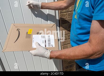 Kurier Mann klopft an Haustüre mit Schutzhandschuhen Lieferung halten Amazon Lieferpaket Paket England Großbritannien GB Großbritannien Stockfoto