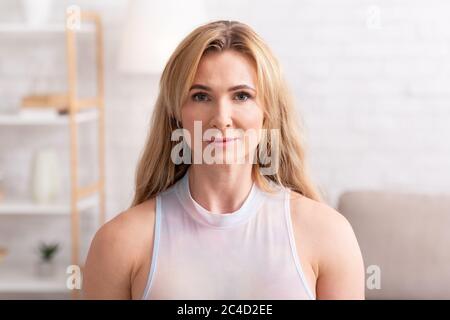 Schöne Frau mittleren Alters bei Tageslicht im Inneren des Hauses Stockfoto