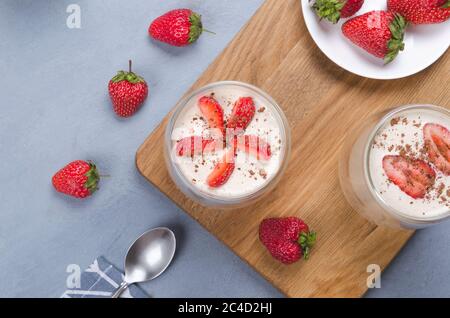 Erdbeerdessert im Glas mit frischen Erdbeeren auf einem grauen Tisch mit Leinenserviette Stockfoto