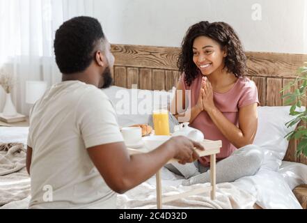 Ehemann überraschend Frau mit Frühstück im Bett Stockfoto