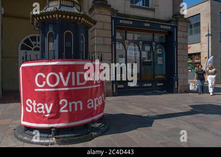 Großes rotes Warnschild Covid-19, 2 m auseinander bleiben, mit geschlossenem Geschäft hinter dem Hotel. Stourbridge. West Midlands. GROSSBRITANNIEN Stockfoto