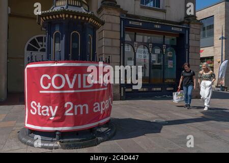 Großes rotes Warnschild Covid-19, 2 m auseinander bleiben, mit geschlossenem Geschäft hinter dem Hotel. Stourbridge. West Midlands. GROSSBRITANNIEN Stockfoto