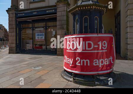 Großes rotes Warnschild Covid-19, 2 m auseinander bleiben, mit geschlossenem Geschäft hinter dem Hotel. Stourbridge. West Midlands. GROSSBRITANNIEN Stockfoto