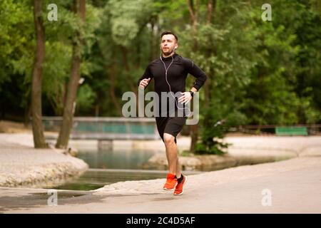 Portrait des fokussierten Jogging-Typen, der im Park läuft Stockfoto