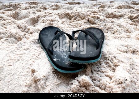 Nahaufnahme von schwarzen Sandalen auf dem Sand Stockfoto