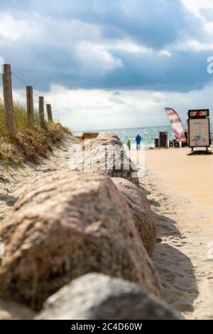 FEHMARN, DEUTSCHLAND - 05. Sep 2019: Ein Weg über eine Düne zum Strand mit touristischen Einrichtungen im Hintergrund und als Weg Grenzsteine und einen Zaun am Th Stockfoto