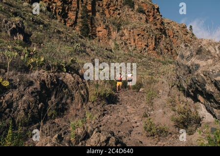 Gruppe junger Erwachsener, die gemeinsam durch Wanderwege am Hang in der Natur trainieren und laufen. Stockfoto