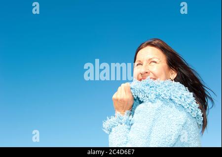 Porträt von selbstbewusst und glücklich entspannt aussehende attraktive ältere Frau genießen aktiven Ruhestand in der Wintersonne, isoliert mit blauen Himmel als Hintergrund Stockfoto