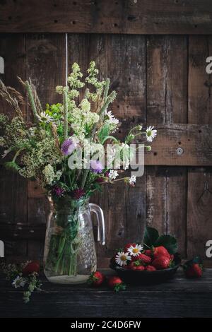 Ländliche Umgebung mit wilden Blumen und Erdbeeren Stockfoto