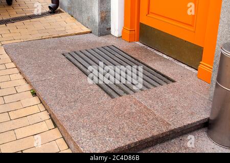 Schwelle einer orangefarbenen hölzernen Eingangstür mit Fußmatte Nahaufnahme Seitenansicht. Stockfoto