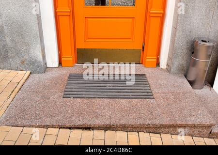 Schwelle einer orangefarbenen Holztür mit Fußmatte Nahaufnahme Vorderansicht. Stockfoto
