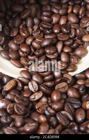 Nahaufnahme von frisch gerösteten Kaffeebohnen, die aus einem auslaufen Weißer Becher Stockfoto