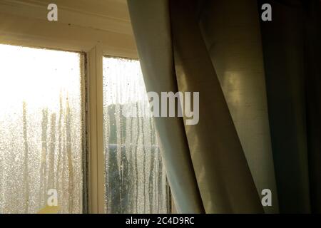 Das Innere eines alten Häuschen, das während eines Winters morgens starke Kondensation auf den Innenfenstern zeigt. Die Holzrahmen sind sichtbar. Stockfoto