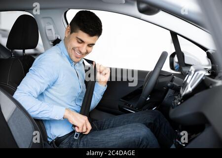 Lächelnder Kerl, Der Den Sicherheitsgurt Anlegt, Der Im Auto Sitzt Stockfoto