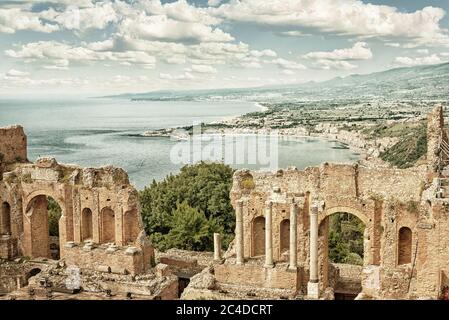 Das antike römisch-griechische Amphitheater mit der Giardini Naxos Bucht im Hintergrund in Taormina, Sizilien, Italien (HDR Bild mit schwarz-goldenem Filter) Stockfoto