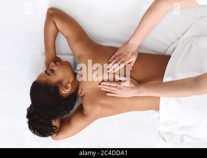 Ruhige afrikanische Mädchen bekommen zurück massage, weißer Hintergrund Stockfoto