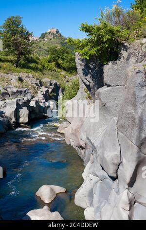 Fluss Alcantara, der durch die Lavasteine des Ätna und die Türme von Castiglione im Rücken in Sizilien, Italien geht Stockfoto