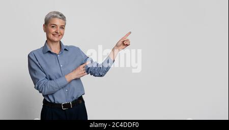 Lächelnde Geschäftsfrau Mittleren Alters, Die Mit Zwei Händen Auf Copy Space Zeigt Und Etwas Empfiehlt Stockfoto