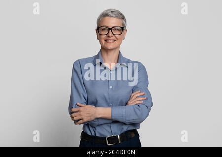 Porträt Von Attraktiven Reifen Geschäftsfrau In Stilvollen Brillen Posiert Mit Gefalteten Armen Stockfoto