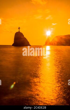 Ein rot brennender Sonnenuntergang mit dem Silhouett einer Klippe über dem Meer Stockfoto