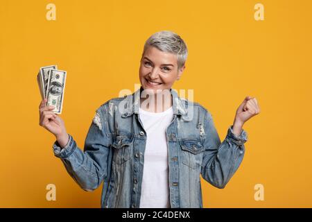 Viel Glück. Aufgeregt Reife Frau Holding Dollar Cash, Gestikuling Ja, Erfolg Feiern Stockfoto