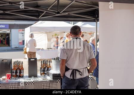 Der Kreditmarkt-Trader, der hinter sich steht, ist am Stall. Auf dem Tisch sind verschiedene abgefüllte Produkte zu sehen. Stockfoto