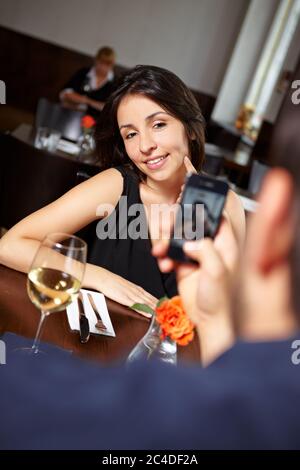 Mann mit Handy fotografiert Frau im Restaurant Stockfoto