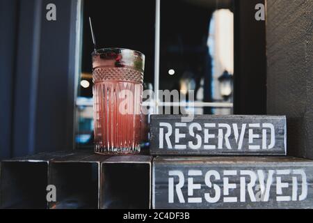 Frischer Granatapfel-Cocktail im Restaurant. Erfrischende Limonade im schönen Glas. Metall-Schild. Tischreservierung in Bar. Stockfoto