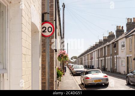 Terrassenförmige Straße mit einem Schild mit einem Geschwindigkeitsbegrenzer von 20 km/h. Die historischen, alten Häuser sind zusammen mit geparkten Fahrzeugen zu sehen. Oft als eine verkehrsreiche Pendlerstraße verwendet Stockfoto