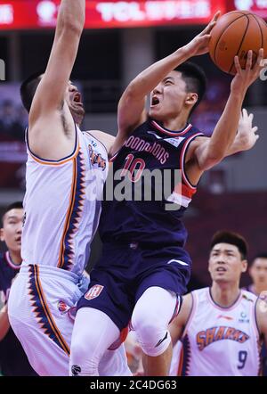 Qingdao, Chinas Provinz Guangdong. Juni 2020. Tian Yuheng (Front, R) von Guangzhou Loong Lions geht bei einem Spiel zwischen Shanghai Sharks und Guangzhou Loong Lions in der neu wiederaufgenommenen Liga der Chinesischen Basketballvereinigung (CBA) 2019-2020 in Dongguan, südchinesische Provinz Guangdong, 26. Juni 2020, in einen Korb. Quelle: Li Ziheng/Xinhua/Alamy Live News Stockfoto