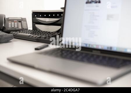 Geringer Fokus eines entfernten VoIP-Telefons und einer Schreibtischschublade, wie man es bei einem typischen Büroschreibtisch sieht. Stockfoto