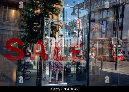 Nachdem in den letzten 24 Stunden weitere 149 Menschen an Coronavirus starben und die Todesrate in Großbritannien auf 43,320 annahmen, werden die Käufer durch das Verkaufsfenster im Geschäft „Zara“ Oxford Street verzerrt, das kürzlich das Geschäft mit Foir wieder eröffnet hat, nachdem die staatlichen Sperrregeln gelockert wurden. Die Flaggen von Union Jack hängen neben den Dankesbannern zur Unterstützung der wichtigsten Mitarbeiter des NHS (National Health Service) während der Covid-Pandemie am 25. Juni 2020 in London, England. Stockfoto