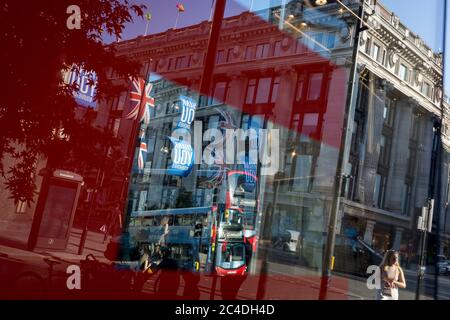 Nachdem in den letzten 24 Stunden weitere 149 Menschen an Coronavirus starben und die Todesrate in Großbritannien auf 43,320 annahmen, werden die Käufer durch das Verkaufsfenster im Geschäft „Zara“ Oxford Street verzerrt, das kürzlich das Geschäft mit Foir wieder eröffnet hat, nachdem die staatlichen Sperrregeln gelockert wurden. Die Flaggen von Union Jack hängen neben den Dankesbannern zur Unterstützung der wichtigsten Mitarbeiter des NHS (National Health Service) während der Covid-Pandemie am 25. Juni 2020 in London, England. Stockfoto