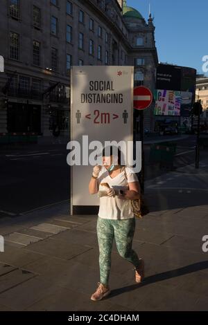 Nachdem weitere 149 Menschen in den letzten 24 Stunden an Coronavirus starben, was die Todesrate in Großbritannien auf 43,320 annahm, geht ein maskierter Londoner, der Eis isst, während der Covid-Pandemie am 25. Juni 2020 in London, England, an den Regeln für soziale Fernberatung auf der Regent Street vorbei. Stockfoto