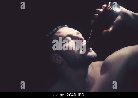 Nahaufnahme eines starken Mannes, der eine Flasche Bier trinkt Stockfoto