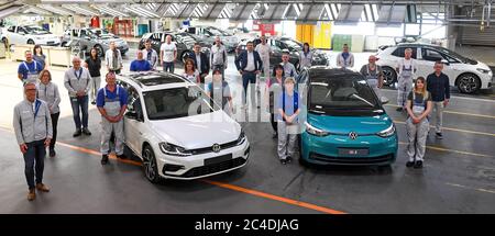 26. Juni 2020, Sachsen, Zwickau: Mitarbeiter des Volkswagen-Sachsen-Werks stehen im Ziel der Linie um eine VW Golf-Variante und neben der neuen ID.3 nach mehr als sechs Millionen produzierten Autos rollt nun der letzte Verbrennungsmotor vom Fließband. Damit ist eine Ära am traditionsreichen Automobilstandort Zwickau beendet. Bereits im November hatte VW in seinem Werk in Sachsen mit der Serienproduktion des vollelektrischen ID.3 begonnen. Die Produktion soll schrittweise von 1500 Fahrzeugen pro Tag hochgefahren werden. Das Elektroauto soll im September auf den Markt kommen. Foto: Hendrik S Stockfoto