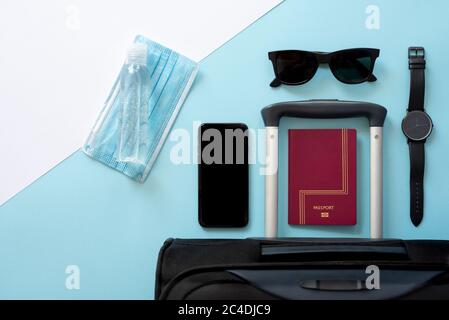 Horizontales Farbbild mit einer Ansicht von oben auf einem Reisenden Zubehör auf einem Sommerurlaub 2020 mit dem Coronavirus auf einem blau-weißen Hintergrund. Stockfoto