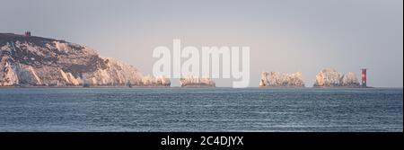 Die berühmten Nadeln felsigen Ausbissen einschließlich Leuchtturm in warmen getaucht Licht am frühen Morgen Stockfoto