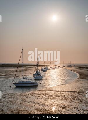 Am frühen Morgen geht die Sonne über Booten vor Anker im Kanal des Wassers in Keyhaven, Hampshire, Großbritannien Stockfoto