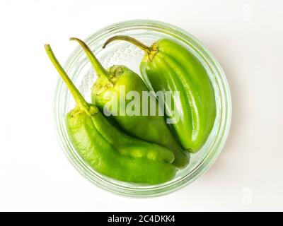 Frische grüne Chilischoten in einer Glasschale mit Ramekin auf weißem Hintergrund Stockfoto