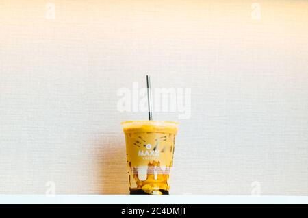 Ein illustrativer Leitartikel des Maxx Coffee Iced Coffee mit Karamell und einem Edelstahlstroh in der Mitte mit einem hellrosa Hintergrund. Stockfoto