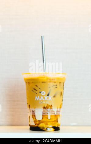 Ein illustrativer Leitartikel des Maxx Coffee Iced Coffee mit Karamell und einem Edelstahlstroh in der Mitte mit einem hellrosa Hintergrund. Stockfoto