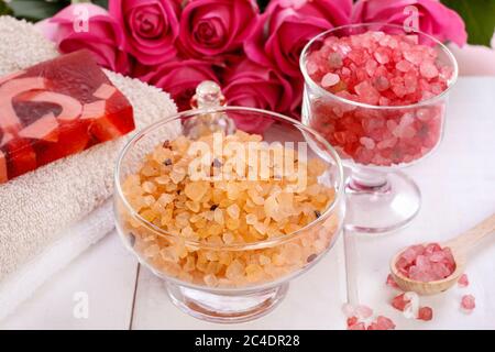 Glasschale mit gelbem Meersalz. Rosa Rosen im Hintergrund. Spa-Zeit Stockfoto