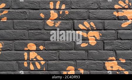 Orangene Handdrucke auf schwarzer Ziegelwand. Hintergrund. Stockfoto