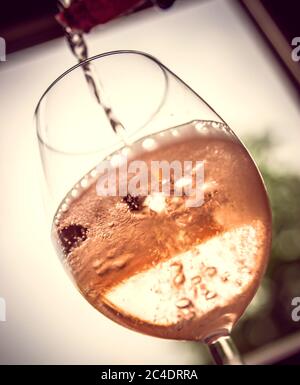 Gießen Sie Rosé in Weinglas Stockfoto