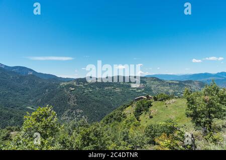 Landschaft der Pyrenäen mit einem Bauernhaus und einem Dorf im Hintergrund. Tourismus, Ruhe, stressfrei, Friedenskonzept. Verbindung mit Stockfoto