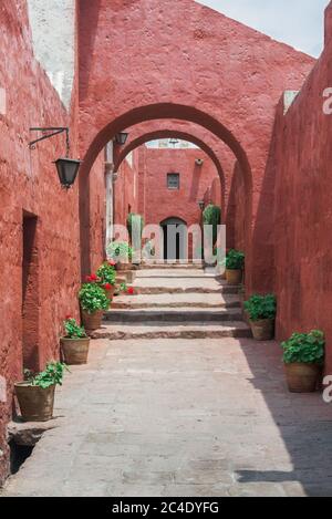 Schöne schmale Straße mit Blumentöpfen und roten Kolonialgebäuden im Kloster Santa Catalina, Arequipa, Peru Stockfoto