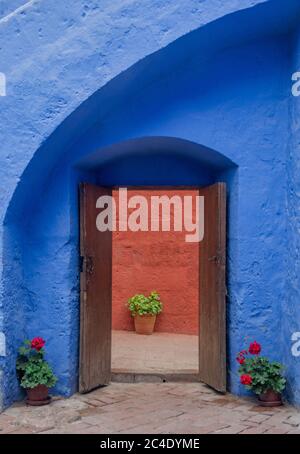 Malerische und bunte Ecke mit Blumentöpfen, alte geöffnete Tür und schöne blaue Wand im Kloster Santa Catalina in Arequipa, Peru Stockfoto