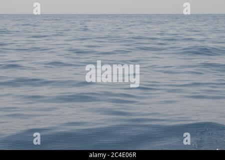 Ein glattes, stahlfarbenes Meer, das sich bis zum Horizont ausdehnt Stockfoto